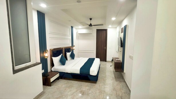 Un dormitorio moderno con una cama grande, una mesita de noche, un televisor y un ventilador de techo.