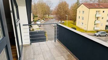 Ein Balkon mit Blick auf einen Parkplatz und ein Gebäude gegenüber.