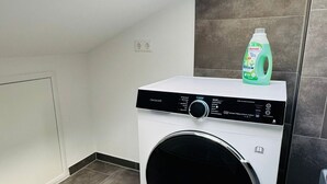 Ett kompakt och modernt tvättrum med inbyggd tvättmaskin och torktumlare, ett takfönster och ett klinkergolv.