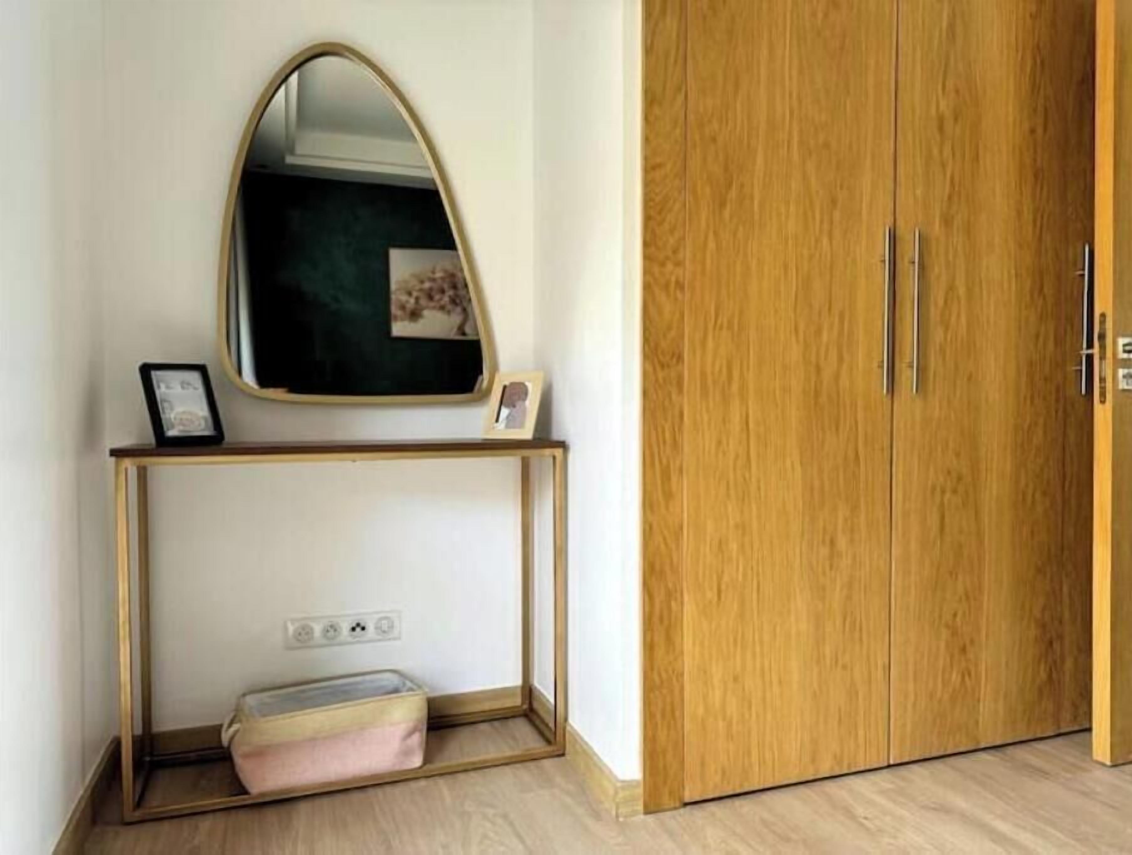Una habitación con un armario de madera, una consola con espejo y un pequeño banco.