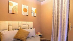 A hotel room with a bed, a nightstand, and three wall-mounted artworks. - Cosy calm Studio in the hyper center (Agadir)