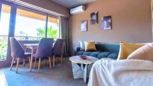 A modern room with a balcony, a sofa, a dining table with chairs, and a small round table with a bowl. - Cosy calm Studio in the hyper center (Agadir)
