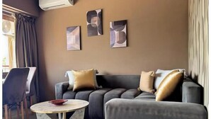 A modern living room with a grey sofa, two round coffee tables, and abstract wall art. - Cosy calm Studio in the hyper center (Agadir)