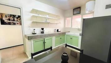 A compact kitchen with green cabinets, a black countertop, and a refrigerator.
