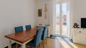 Een eethoek met een houten tafel, blauwe stoelen, een witte kast en een televisie.