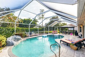 A covered outdoor swimming pool with lounge chairs and a barbecue area. - Private Pool, Firepit, Game Room Mins to Beaches + Community Amenities Casa Solara by Avantstay (Naples)