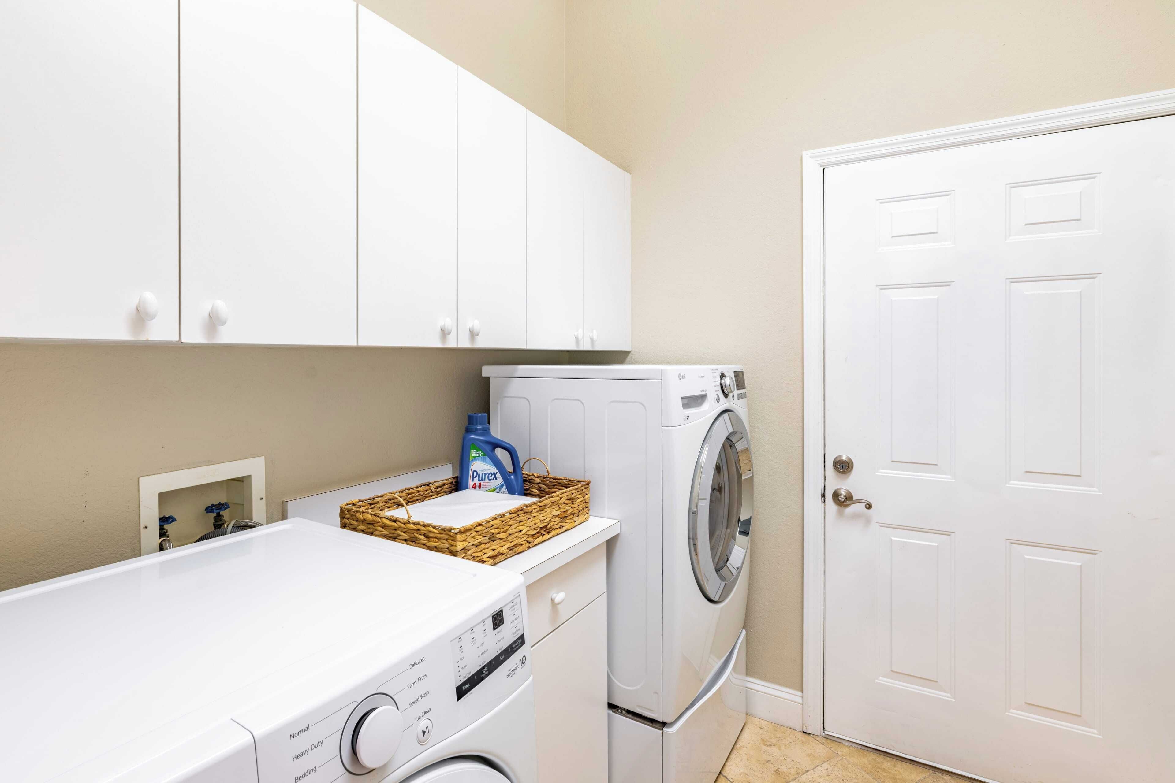 A laundry area with a washing machine, dryer, and cabinets.