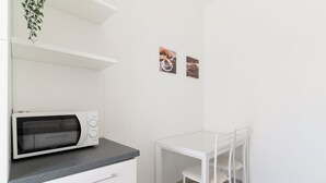 Een kitchenette met een magnetron, een witte tafel en twee stoelen.