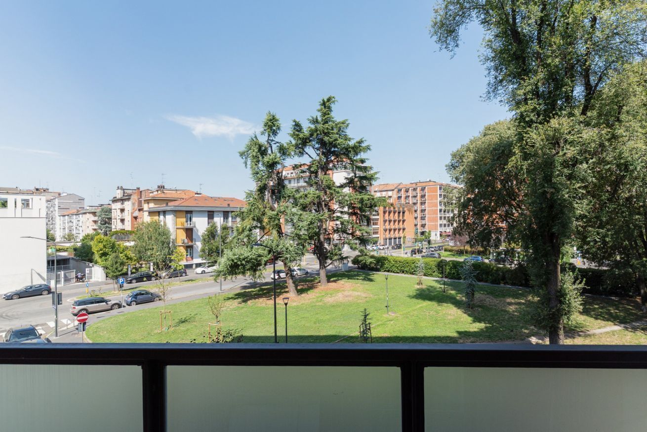 A residential area with apartment buildings, a grassy park, and a street.