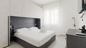 Een moderne hotelkamer met een groot bed, een bureau en een televisie.