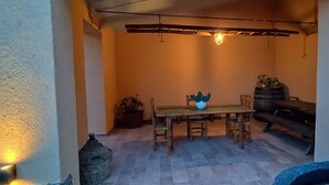 A cozy patio area with a wooden table and chairs, a hanging light fixture, and a barrel. - Apartment in Farmhouse with 2 bedrooms and 2 bathrooms nestled in the Tuscan Maremma (Gavorrano)