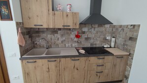 A kitchen with wooden cabinets, a black sink, and a tiled backsplash. - Apartment in Farmhouse with 2 bedrooms and 2 bathrooms nestled in the Tuscan Maremma (Gavorrano)
