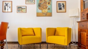 Une pièce avec deux fauteuils jaunes, un meuble en bois et un sol à motifs.