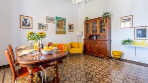 Un coin repas avec une table en bois, des chaises, un vase rempli de tournesols et un buffet aux portes en verre.