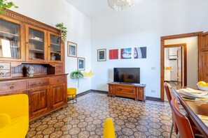 Ein Wohnzimmer mit Fernseher, Holzschränken, einem gemusterten Boden und einem Essbereich.