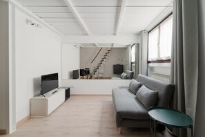 Una sala de estar moderna con un sofá, un televisor y una mesita.
