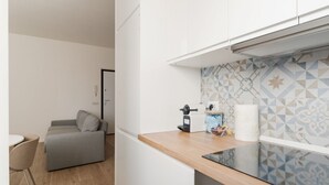 Eine kleine Küche mit einer Holzarbeitsplatte, einer Kaffeemaschine und einer gemusterten Spritzschutzleiste.