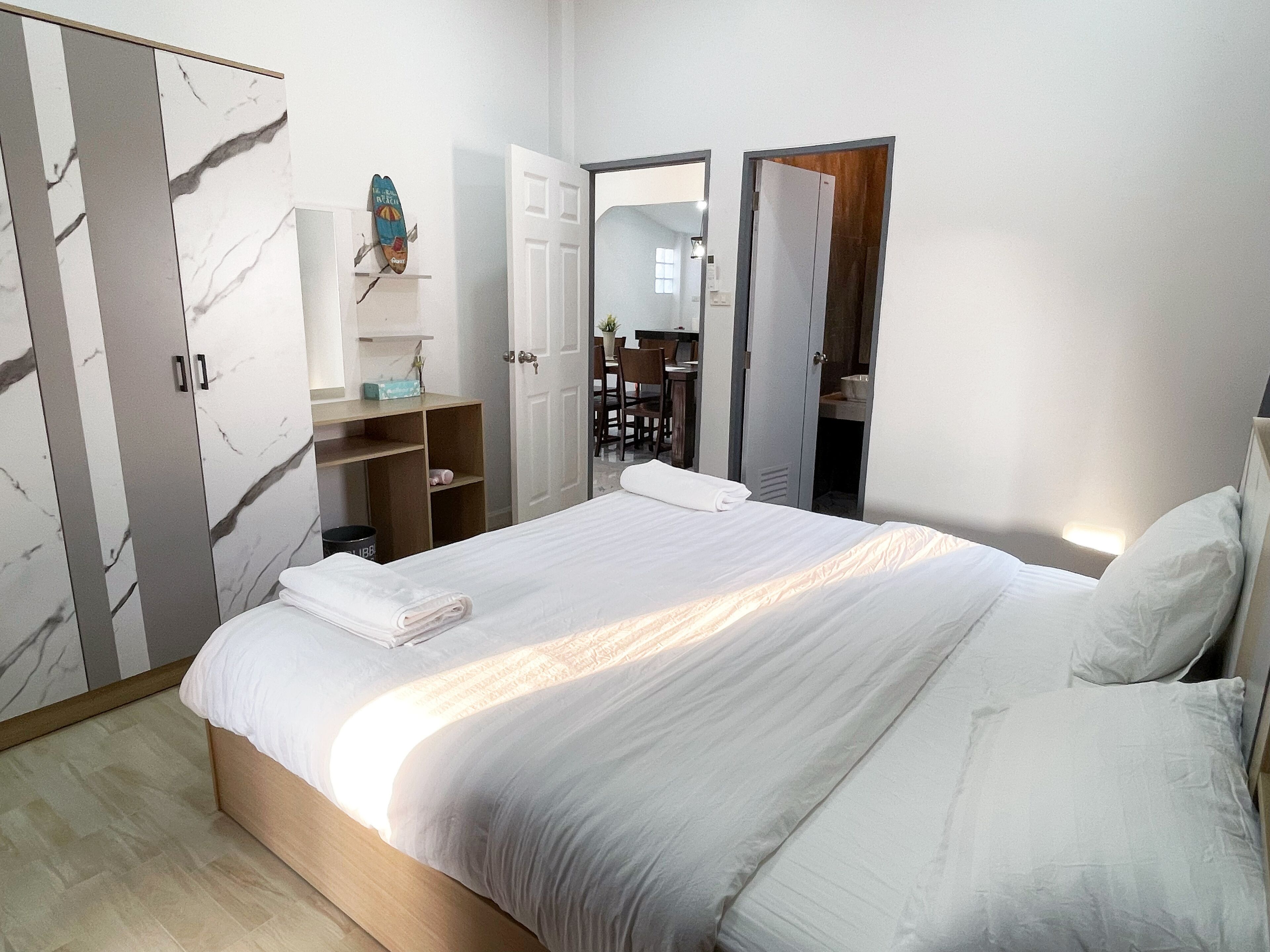 Un dormitorio con cama, armario, escritorio y espejo.