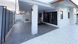 A modern house with a covered patio, large windows, and a tiled floor.