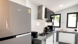 A modern kitchen with a refrigerator, stove, and coffee maker.