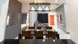 A modern dining area with a marble table, chairs, and a chandelier.