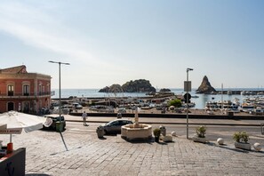 A coastal town with a marina, a fountain, and a red building with a sign.