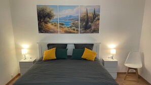 A bedroom with a bed, two nightstands, a chair, and three paintings on the wall. - Large Duplex Apartment 85m2 (Fleurieux-sur-l'Arbresle)