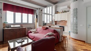 En kompakt bolig med tekøkken, spiseplads og opholdsområde med sofa og bord.