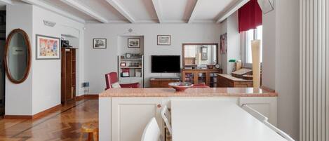 A spacious living area with a kitchen, dining table, and a large mirror.