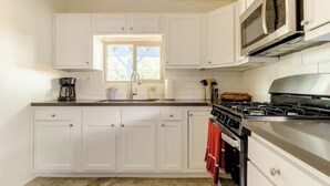A kitchen with white cabinets, a gas stove, a microwave, and a window above the sink. - Central pet-friendly private house located by U of A with pool and hot tub (Tucson)