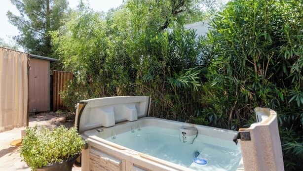 A hot tub in a backyard with dense foliage in the background. - Central pet-friendly private house located by U of A with pool and hot tub (Tucson)