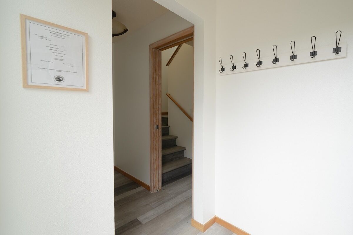 Een gang met een lijst waarop een certificaat hangt, een houten trap en een aantal zwarte klemmen aan de muur.
