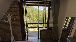 Una habitación con un ventanal grande, un perchero y vistas a la vegetación exterior.