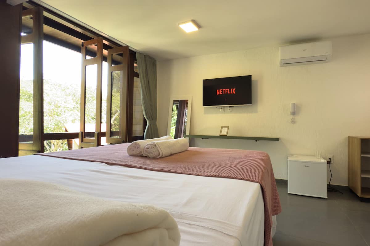 A hotel room with a bed, a television mounted on the wall, and a small refrigerator.