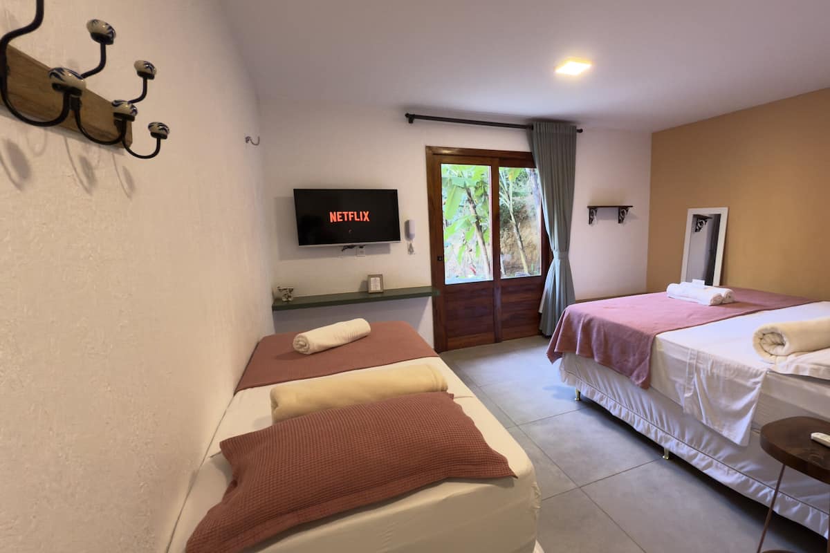 A hotel room with two beds, a TV, a mirror, and a small table.