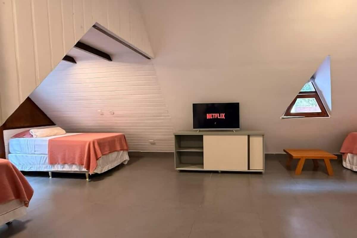 A room with two beds, a TV, a small table, and a window.