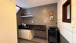 Una cocina compacta con encimera negra, armarios blancos y lavavajillas integrado.