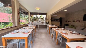 Un comedor con mesas dispuestas para cuatro, una zona de cocina y un área de estar con un sofá.