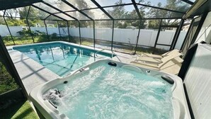 Un jacuzzi con recinto de vidrio, una piscina y vistas al exterior.