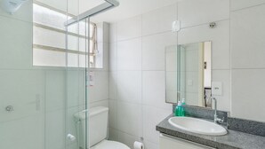 A modern bathroom with a glass shower enclosure, a toilet, a sink with a granite countertop, and a large mirror. - Studio 750m From Redencao Park Hpn0618 (Porto Alegre)