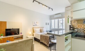 A modern hotel room with a bed, a TV, a desk, and a kitchenette. - Studio 750m From Redencao Park Hpn0618 (Porto Alegre)