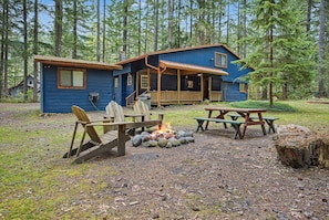 Eine Hütte mit Veranda, Feuerstelle und Picknicktischen.