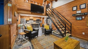 A wooden interior with a staircase, a flat-screen TV, and a kitchen area. - Mt Hood Cabin Sanctuary with Hot Tub, Pets Welcome (Mount Hood Village)