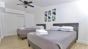 A bedroom with two beds, a ceiling fan, and artwork on the wall.