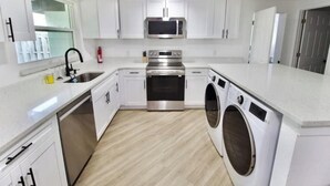 A modern kitchen with white cabinets, stainless steel appliances, and a built-in washing machine.