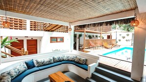 Um interior moderno com uma área de estar em curva, uma piscina e uma escadaria para um pátio ao ar livre.