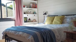 Une chambre à coucher avec un lit, une table de chevet, une bibliothèque et une fenêtre avec des rideaux.