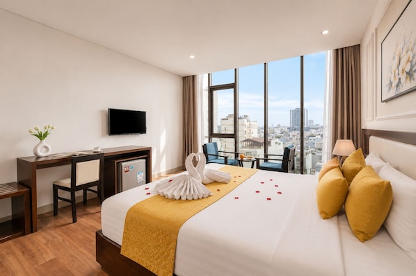 A hotel room with a bed, a desk, a television, and a city view. - Sapphire Hotel (Da Nang Municipality)