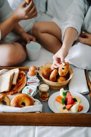 A breakfast tray with bread, eggs, butter, and a fruit salad. - Sapphire Hotel (Da Nang Municipality)