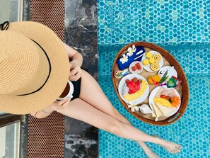 A person relaxing by a pool with a tray of food and a drink. - Sapphire Hotel (Da Nang)